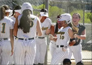  ?? Photos by Katherine Quezada/ The Signal ?? (Above left) Canyon junior Jessica Carr (16) pitches during her team’s game against against Golden Valley at Canyon High School on Tuesday. (Above right) Canyon players cheer for teammate Karina Montero (10) after she hits a home run.