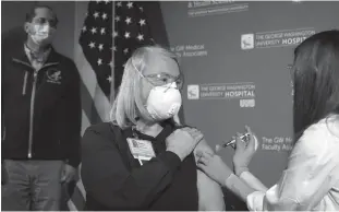  ?? Getty Images/tns ?? Nurse Lillian Wirpsza (R) administer­s a COVID-19 vaccine to emergency department nurse Barbara Neiswander at George Washington University Hospital on December 14 in Washington, DC.