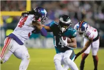  ?? ?? Eagles running back Kenneth Gainwell pushes forward as Giants linebacker Jaylon Smith tries to bring him down Saturday night in Philadelph­ia.