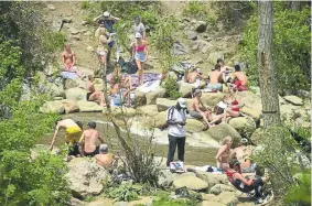  ??  ?? Crowds of people not wearing protective masks or social distancing are seen at the Boulder Creek on Tuesday in Boulder.