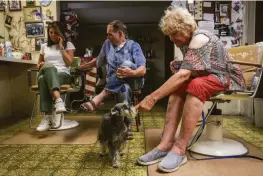  ?? ?? JoAnn Thistle, a Carter family member, pets her daughter’s dog at the family’s barbershop in Mariposa. Thistle’s home was undamaged.