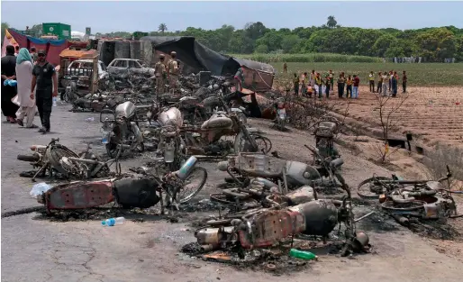  ?? AP file ?? Army soldiers stands guard while rescue workers examine the site of the oil tanker explosion at a highway near Bahawalpur on June 25. —