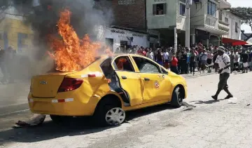  ??  ?? Residents looking at a burning taxi set on fire by a a violent mob that lynched two men and a woman whom they accuse of stealing children and were travelling on it, police authoritie­s informed, at Posorja, Ecuador. — AFP photo