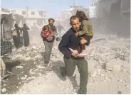  ?? Amer Almohibany / AFP / Getty Images ?? Syrians flee through debris after an air strike in the rebel-held town of Beit Sawa, outside Damascus.