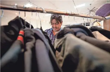  ?? DIANNIE CHAVEZ/THE REPUBLIC ?? Esteban Diaz, store manager, puts price tags on clothing at Thrift to Thrive in Phoenix on Nov. 14.