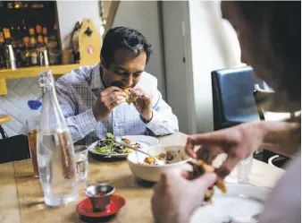  ??  ?? Top: Sous chef Kyle Wernke (center) calls to a waiter to tell him the Impossible Burgers are ready to serve at Cockscomb restaurant in San Francisco. Above: Sameer Narang (left) bites into an Impossible Burger during lunch with Jay Gierak at Cockscomb.