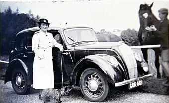  ??  ?? Another photograph from the family album. This image shows a woman dressed in formal clothing standing next to a large car while holding a terrier-type dog on a lead. A man, stroking a horse, can be seen standing in the background. The shop is keen to...