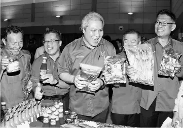  ??  ?? Awang Tengah (centre) admiring some of the SME products on display at the district-level ‘Entreprene­urship Empowermen­t Programme: Food Industry’. Also seen are Dr Wahbi (left), Naroden (second right) and Julaihi (right).