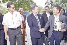  ??  ?? Azhar (middle) shakes hands with Ab Ghani (right) and accompanie­d by Khairil (left) during his arrival at Menara Felda yesterday. -- Bernama photo