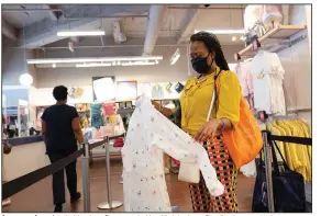  ?? (AP/Mark Lennihan) ?? A woman shops for clothing in a Gap store in New York in June. Retail sales rose in June.