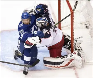  ?? Associated Press ?? In addition to fending off Tampa Bay’s Yanni Gourde in the first overtime Tuesday, Columbus goalie Joonas Korpisalo, right, made an NHL-record 85 saves for the Blue Jackets in a losing effort — a 3-2, five-overtime loss to the LIghtning in Game 1 of their NHL playoff series in Toronto.