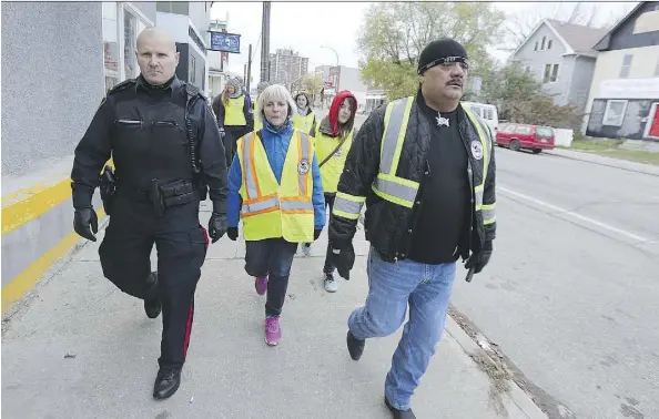  ?? KEVIN KING ?? Winnipeg police Const. Jeff Boehm, left, walks with a group lead by Bear Clan Patrol organizer James Favel. Since 2015, Favel and his team have evolved the patrol’s mandate — upgrading to become a welcome wagon, resource service, cleanup crew, conflict...