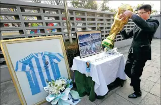  ?? WEI XIAOHAO / CHINA DAILY ?? An employee of the Argentine embassy in China sets a table for a memorial to soccer legend Diego Maradona at the embassy in Beijing on Thursday. Fans visited the embassy to pay tribute to Maradona, one of the greatest soccer players of all time.