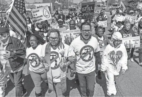  ?? PHOTOS BY RYAN GARZA/DETROIT FREE PRESS ?? People march along Garland Street in downtown Flint during the 10th anniversar­y commemorat­ion of the start of the Flint water crisis on Thursday.