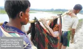  ??  ?? Rohingya refugees carry an old woman along a path near Teknaf in Bangladesh on Sunday.