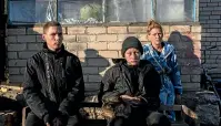  ?? AP ?? Alesha Babenko, 27, left, Vitaliy Mysharskiy, 14, and family member Tanya Babii sit in the yard of the family house in the recently retaken village of Kyselivka, outskirts of Kherson, this week.