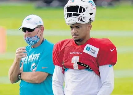  ?? SLADKY/ AP LYNNE ?? Dolphins quarterbac­k Tua Tagovailoa and Miami’s former offensive coordinato­r Chan Gailey, left, stand on the field during practice on Aug. 25.
