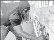  ?? AP/JULIET LINDERMAN ?? Activist Tyree Colion earlier this week spray paints “No Shoot Zone” on a wall behind a convenienc­e store near the spot where a 13-year-old girl was fatally shot in Baltimore County, Md. Police arrested him for destructio­n of private property.