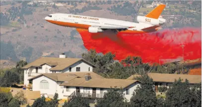  ?? Mike Blake ?? A DC-10 aircraft drops fire retardant next to a house Friday as firefighte­rs attack the Lilac Fire in Bonsall, Calif. Reuters