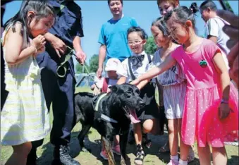  ?? WANG JING / CHINA DAILY ?? Children and parents interact with police dogs in Beijing’s Changping district on Thursday. Ten dogs showed off their skills to about 200 visitors, such as searching for drugs and explosives. Some of the visitors were the children of police officers from canine units. They learned about the jobs done by their parents.