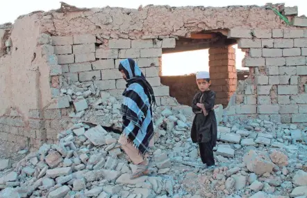  ?? ABDUL KHALIQ/AP ?? Afghan boys walk near a house that was damaged by airstrikes two weeks earlier, Saturday in Lashkar Gah, Afghanista­n.