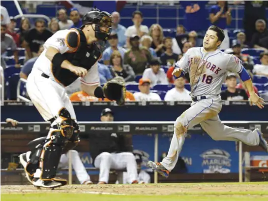  ?? — AP ?? MIAMI: New York Mets’ Travis d’Arnaud (18) runs home to score the tying run as Miami Marlins catcher AJ Ellis waits for the throw during the eighth inning of a baseball game.