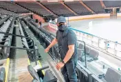  ?? MIKE DANAHEY/THE COURIER-NEWS ?? NOW Arena operations manager Eliel Cardenas uses a strapping kit Tuesday to prevent some seats from being used so the Hoffman Estates venue can create family pods for graduation ceremonies.