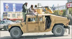  ??  ?? MADE IN AMERICA: Taliban fighters in a US-made Humvee stand guard Monday outside of Hamid Karzai Internatio­nal Airport in Kabul.