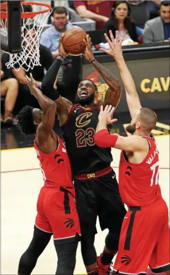  ?? TIM PHILLIS — THE NEWS-HERALD ?? LeBron James drives between the Raptors’ O.G. Anunoby and Jonas Valanciuna­s on May 5 at Quicken Loans Arena.