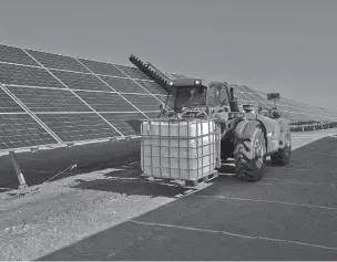  ??  ?? A tractor is used to clean photovolta­ic panels at a solar park near Calama, Chile. Strong winds stir up dust that coats the panels, reducing their energy output.