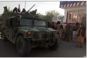  ?? (AP/Abdullah Sahil) ?? Taliban fighters stand guard Monday at a checkpoint in Kunduz, Afghanista­n, one of several provincial capitals now under control of the group.