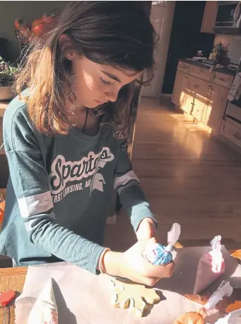  ?? Photos by Susan Clotfelter, special to The Denver Post ?? Shannon Ramey creates a pale-blue design on a gingerbrea­d Christmas cookie at the home of Monica Signer of Berthoud.