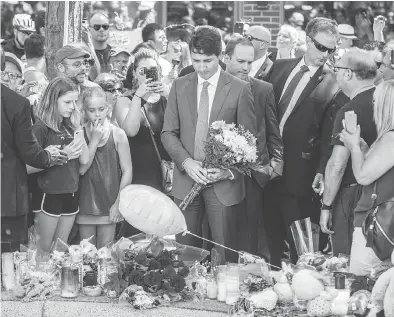  ?? PETER J THOMPSON / NATIONAL POST ?? Prime Minister Justin Trudeau places flowers at a makeshift memorial on Toronto’s Danforth Avenue on Monday for victims of the July 22 mass shooting. “Obviously there’s a lot of strong emotions going on,” he said.