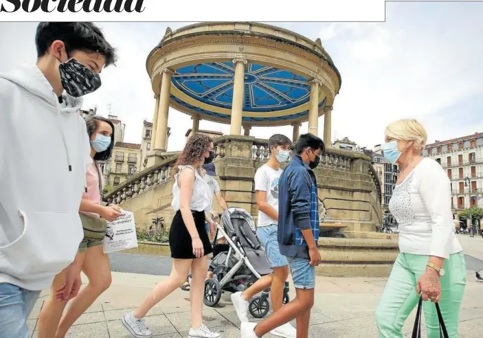  ??  ?? Personas de distintas edades con sus mascarilla­s se cruzan andando por la Plaza del Castillo de Pamplona.