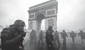  ?? Veronique de Viguerie / Getty Images ?? Tear gas surrounds riot police as they clash with protesters during a demonstrat­ion over increased fuel taxes and government leadership near the Arc de Triomphe in Paris.