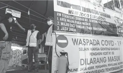  ?? FRIZAL/JAWA POS ?? JANGAN KASIH KENDUR: Warga RT 02, RW 09, Kelurahan Genteng, Kecamatan Genteng, Surabaya, tetap menerapkan protokol kesehatan di gang masuk kampung bagi tamu dan warga.