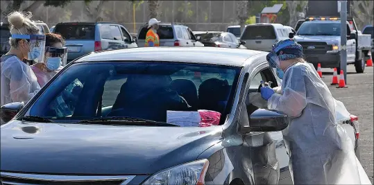  ?? Buy this photo at YumaSun.com FILE PHOTO BY RANDY HOEFT/YUMA SUN ?? YUMA REGIONAL MEDICAL CENTER PERSONNEL CONVERGE ON ONE OF THE VEHICLES to arrive at one of the testing stations in the Yuma Civic Center parking lot during the Yuma Regional Medical Center COVID-19 Testing Blitz on May 9.