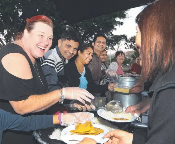  ?? Picture: GLENN HAMPSON ?? Shaz Noy and volunteers from her charity Helping Hands serve the homeless a special Indian feast at Len Fox Park in Labrador.
