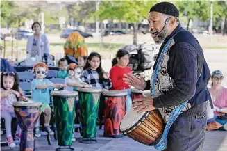  ?? Photos by Michael Wyke/Contributo­r ?? Instructor Sam Dinkins III, right, leads a workshop on hand drumming at Discovery Green.