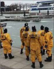  ?? ADAM DODD - THE NEWS HERALD ?? Members of the Cleveland Fire Department look on as they prepare to venture out on to the icy surface of Lake Erie during cold water rescue training with the U. S. Coast Guard, February 13.