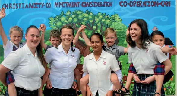  ?? REXINE HAWES ?? Matamata College students Megan Cody, Yasmin Fisher, Vandhana Devi and Shiphrah Foulidis with St Joseph’s School students in front of the mural.