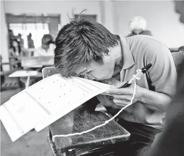  ?? photo — AFP ?? Christophe­r Joaquin, 40, who is partially blind, checks a ballot paper at Jose P. Laurel Senior High School in Manila.