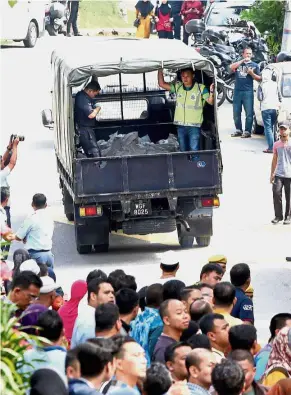  ??  ?? Grim task: Policemen transporti­ng the bodies to Hospital Kuala Lumpur.