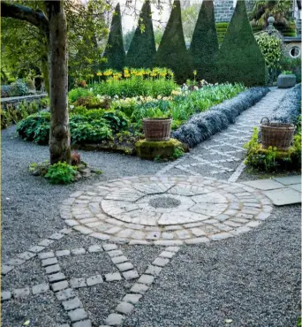  ??  ?? › A striking path of stone setts and gravel in York Gate’s canal garden leads to the focal point of a circular window in the potting shed.
