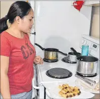  ?? ERIC MCCARTHY/JOURNAL PIONEER ?? Angel Aylward keeps careful watch on a pot as she cooks up some lumpia, a Filipino dish that includes ground pork and chopped vegetables all rolled up in a wrapper and deep-fried.