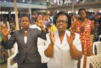  ?? Ben Curtis / Associated Press ?? Rwandans sing and pray at the Evangelica­l Restoratio­n Church in the capital, Kigali. The government says many churches have failed to comply with building safety standards.