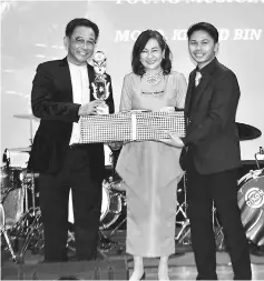 ??  ?? IMH Outstandin­g Young Musician Mohd Khalid Reduan receives his award from Abdul Karim witnessed by Law-Lee.