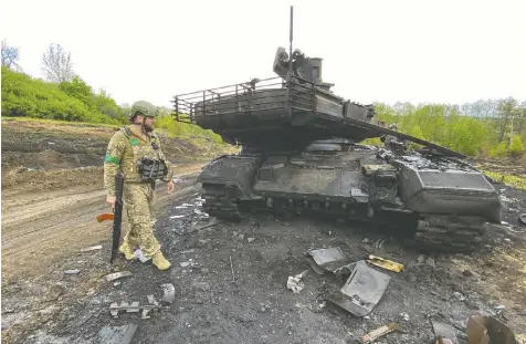  ?? — VITALII HNIDYI/REUTERS ?? A Ukrainian serviceman walks past a destroyed Russian main battle tank T-90M Proryvon Monday as Russia's attack on Ukraine continues, near the village of Staryi Saltiv in Kharkiv region, Ukraine.