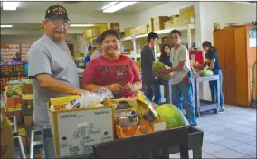 ?? RECORDER PHOTO BY JAMIE A. HUNT ?? Volunteers Rudy Casias and Angelina Chapa at St. Anne’s Food Pantry on Wednesday, July 31, 2019. The food pantry usually serves 100 needy families on Wednesday and Thursdays and is run by the Knights of Columbus and the Catholic Daughters of America.