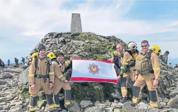  ??  ?? The firefighti­ng team celebrate reaching the summit of Ben Nevis.